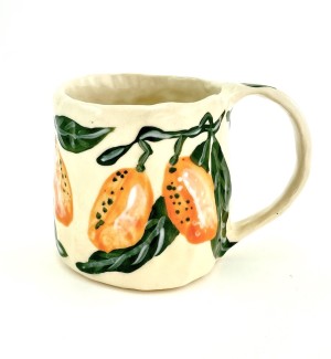 a hand formed ceramic mug with hand illustrated orange kumquats with green leaves.