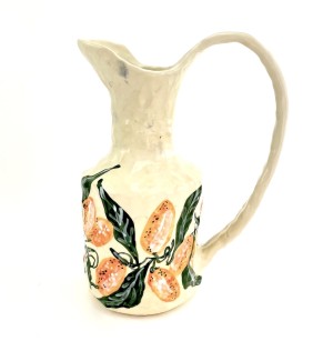 a ceramic pitcher with hand illustrated orange kumquats and green leaves.