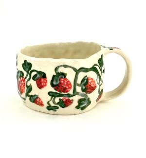 a hand formed ceramic mug with hand illustrated red strawberries and green leaves.