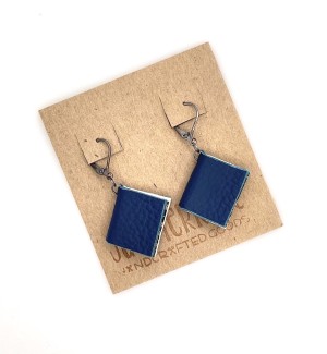 A pair of earrings with small, functional dark blue colored books. 
