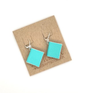 A pair of earrings with small, functional turquoise colored books.