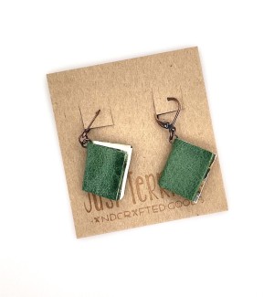 A pair of earrings with small, functional green colored books.