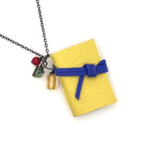 A small yellow hand-bound book hanging on a chain with a blue leather cord tied around it and three small beads. 