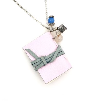 A baby pink hand bound book necklace with a grey cord wrapped around it with three small beads.  
