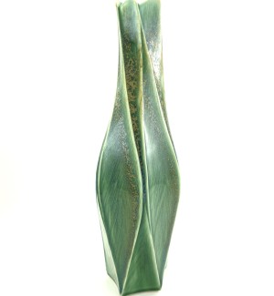 a tall and narrow ceramic vase with facets and carved edges in a celedon green with gold hued highlights.