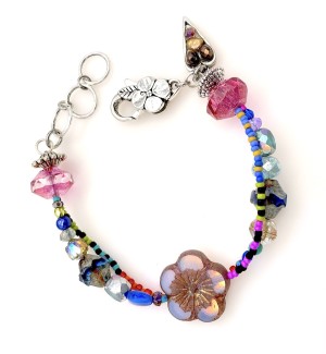 a colorful mixed bead, asymentrical bracelet with a large glass pink flower.