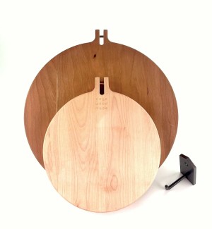 A set of two round cutting boards stacked on top of one another, the top one is a darker shade of wood. 