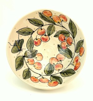 a white ceramic bowl illustrated with clusters of red cherries and green leaves.