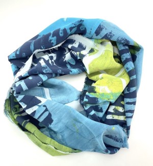 a silk scarf with a blotchy pattern in white, navy blue, citrus green and light blue arranged in a donut shape.