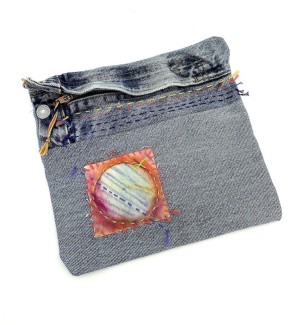 a denim fabric zipper pouch with an embroidered circular patch. 