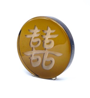 a bronze colored round glass disc with the Chinese character 'Double Joy Double Happiness'. 
