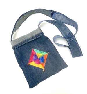 a handsewn blue jean fabric shoulder bag with a hand painted colorful medallion.