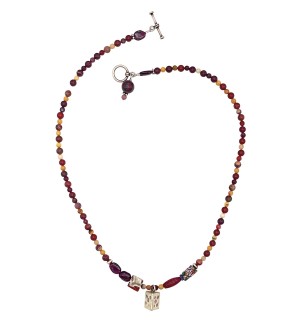 a necklace of strung desert-hued polished round beads with small silver charms and a toggle clasp.
