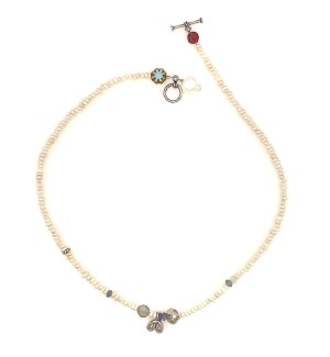 a strung bead necklace of white pearls and a single faceted garnet, moonstone and labradorite bead with a toggle clasp. 