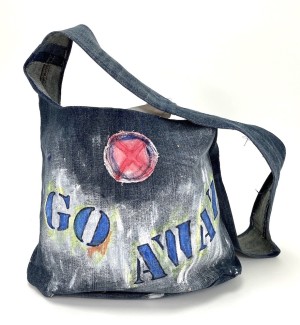 a handsewn shoulder bag of blue jean material with a painted illustration of stenciled letters 'Go Away'.