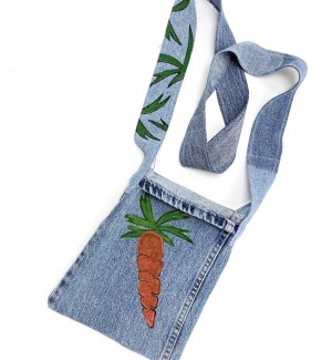 a handsewn shoulder bag of blue jean material with a painted illustration of an orange carrot with green leafy top.