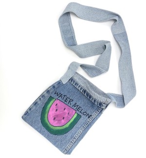 a handsewn shoulder bag of blue jean material with a painted illustration of a slice of pink watermelon, black seeds and green rind.