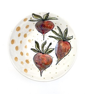 a white ceramic bowl with hand illustrated red beets and green leaves arranged around the interior perimeter.