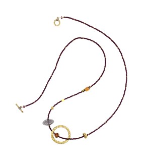 a mixed bead necklace with a maroon and gold strand embellished with a large gold circle and accent beads strung in an asymetrical pattern 