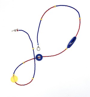 a mixed bead necklace with a red and blue strand embellished with larger blue and yellow accent beads strung in an asymmetrical pattern 