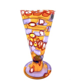 a glass footed cup with a complex pattern of layered, swirly bands of transluscent colors from orange to circles of red and bands of purple.