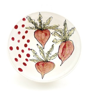 a white ceramic bowl with three hand illustrated red beets with green tops on the right and a field of red dots on the left.