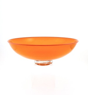 a handblown glass bowl with a low sleek profile, a clear glass foot and an opaque bright orange bowl with a red line at the lip.