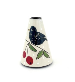 a conal shaped ceramic bud vase with a white background and an illustration of a black bird and red cherries. 