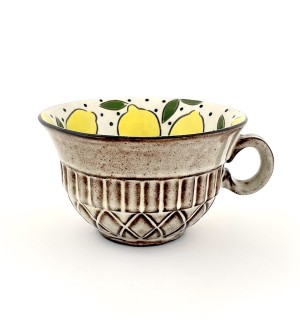 a ceramic mug in the shape of a bowl illustrated interior of lemons and a beige quilted surface exterior.