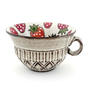 a ceramic mug in the shape of a bowl illustrated interior of strawberries and a beige quilted surface exterior.