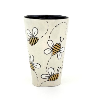 a ceramic tumbler with a white base and illustration of yellow striped bees.