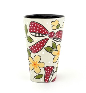 a ceramic tumbler with a white base and illustration of flowers and red bows.