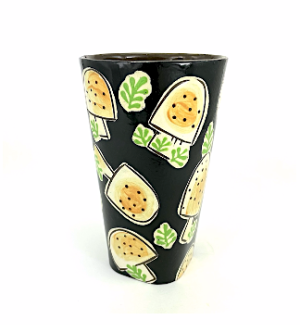 Ceramic tumbler with a black background with button mushrooms with black spots.