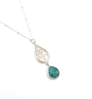 a sterling silver necklace with a beaded chain and a filagree teardrop pendant with a leaf pattern and a bezel set green emerald.