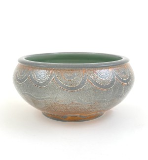 a hand thrown ceramic open bowl with a celadon interior and pebbly mottled grey glaze and a wavy patterned line along the top edge.