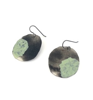 a pair of earrings made of a circular piece of canvas and painted with swatch of green pigment.