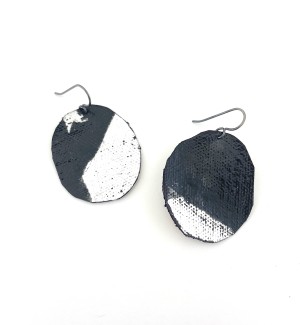 a pair of earrings made of a circular piece of canvas an painted with swatch of black pigment.
