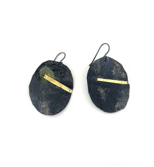 a pair of earrings made of a circular piece of canvas and painted with black pigment and highlighted with a strip of 14k gold.