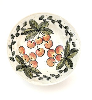 a white ceramic bowl illustrated with clusters of red cherries and green leaves.