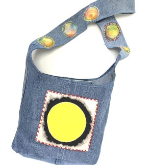 a shoulder bucket bag sewn from blue jeans material with handprinted circles of red and yellow and cross stitched embroidery.