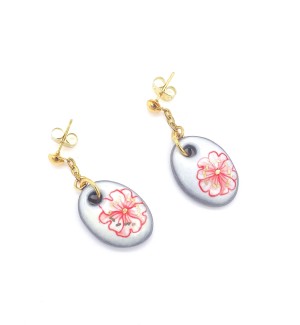 a pair of post style earrings with a short gold chain from which hangs a white oval disc illustrated with a line drawing of a poppy bloom.