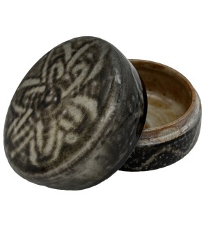 A round ceramic box with the lid propped open on the base