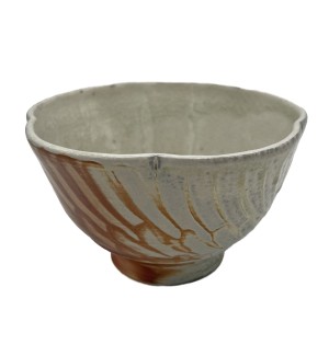 a decorative bowl with a scalloped rim and orange featherlike brushstrokes