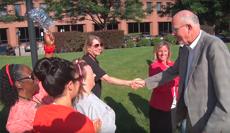 Dr. Munson shakes hands with faculty and staff outdoors