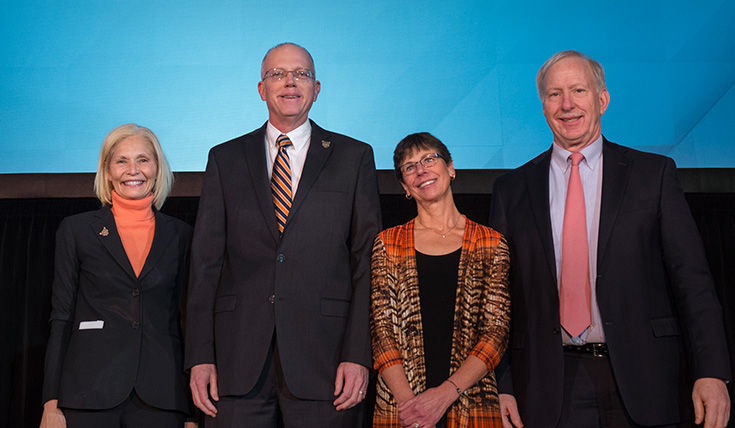 Dr. Munson and his wife standing with 2 people on a stage