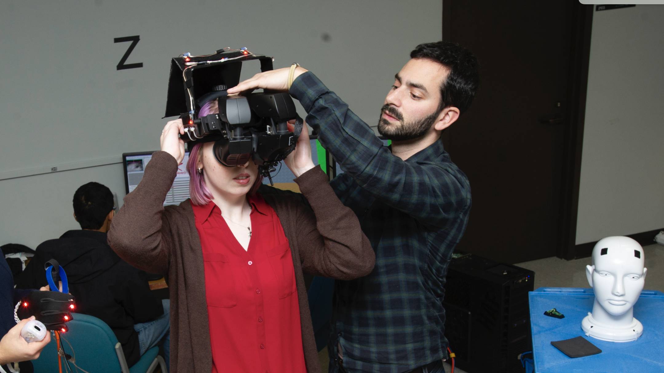 Woman in a red shirt getting fitted for VR goggles