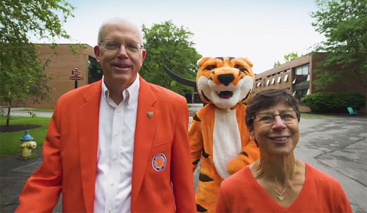 President munson, his wife, and RITchie walking on campus in orange blazers