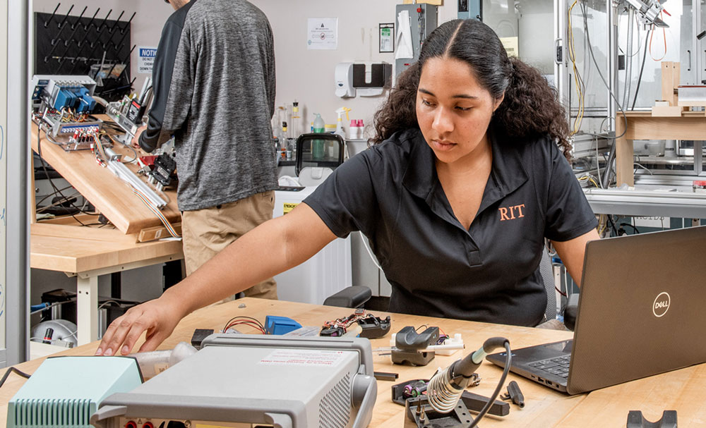 Student working on putting together a robot with parts on the desk.