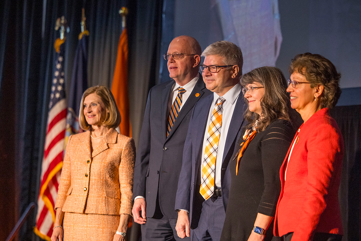 President Sanders stands with his wife, former President Munson, and his wife, and board chair Susan Puglia.