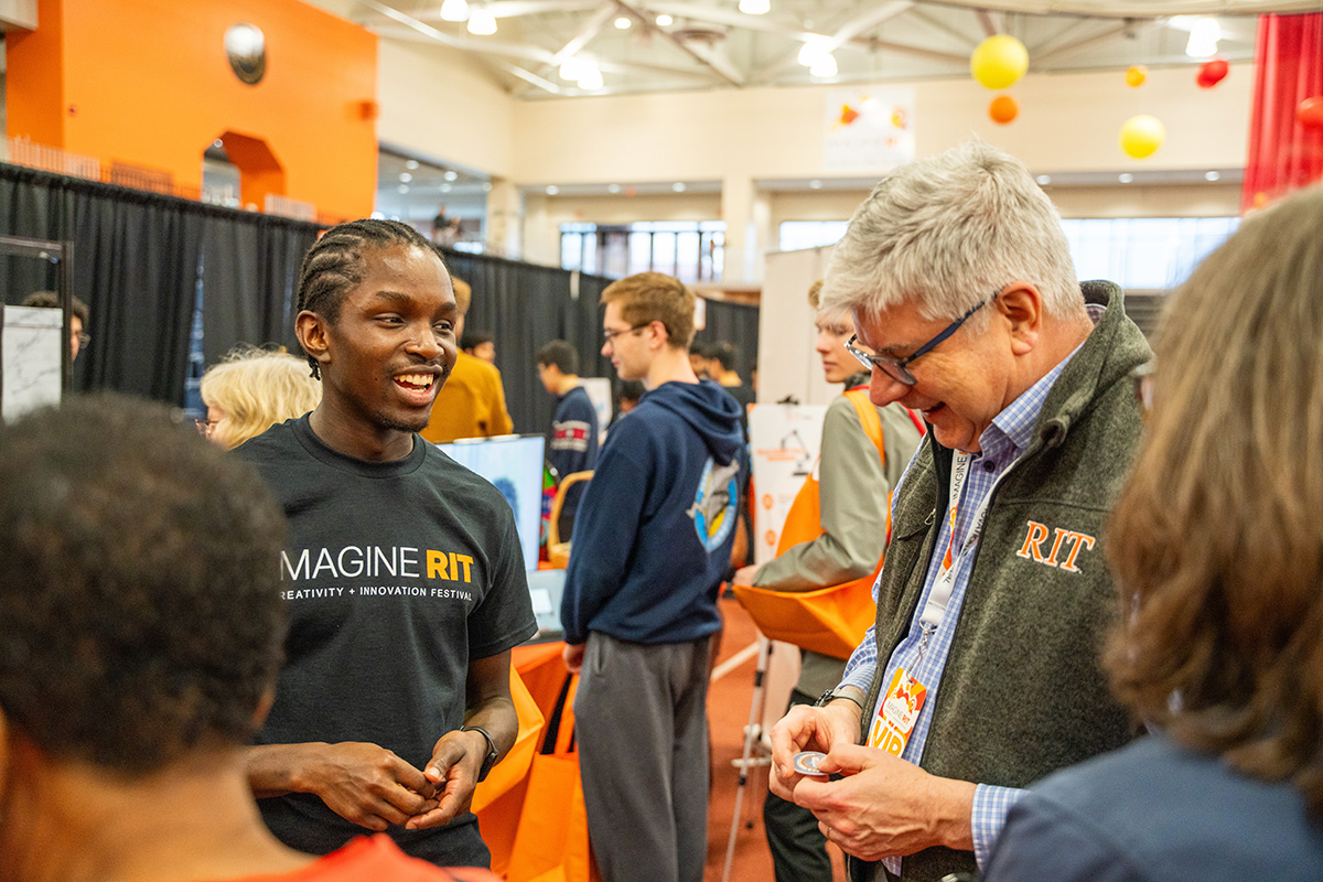 President Sanders attends Imagine RIT, and speaks to a student presenting.